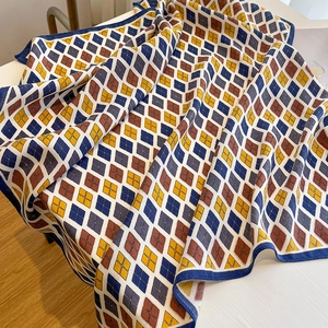 Detailed view of argyle knit scarf featuring blue, yellow, and brown geometric patterns
