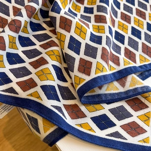 Detail of diamond pattern silk scarf with navy blue borders and soft draped texture