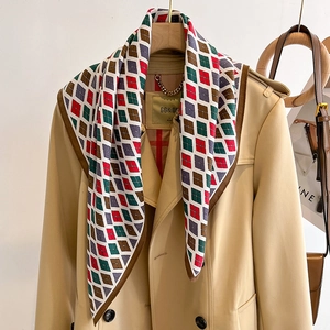 Elegant diamond pattern silk scarf in red and green styled with a beige trench coat
