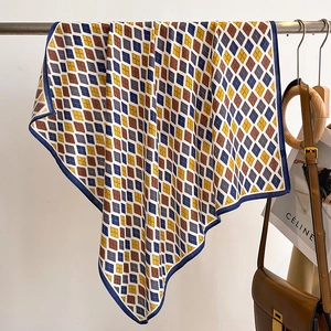 Detail showing the colorful argyle pattern and fine stitched edges of the silk scarf