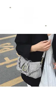Detail of grey pleated cloud bag featuring a textured fabric and gold horseshoe buckle