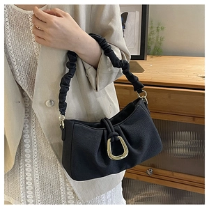 Detail of black pleated fabric underarm bag with gold metal U-shaped buckle decoration