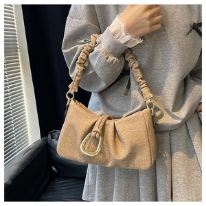 Detail of light khaki woven shoulder bag with golden horseshoe buckle and ruched strap