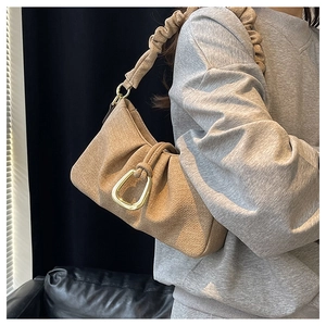 Detail of khaki pleated underarm bag featuring woven texture and golden U-shaped buckle