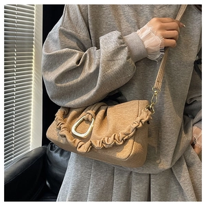 Detail of khaki pleated cloud bag with gold trapezoidal buckle and thin shoulder strap