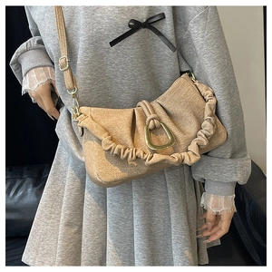Detail of khaki pleated cloud bag showing golden horseshoe buckle and textured fabric