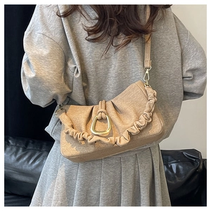 Detail of beige textured fabric shoulder bag with golden metal ring and pleated cloud strap