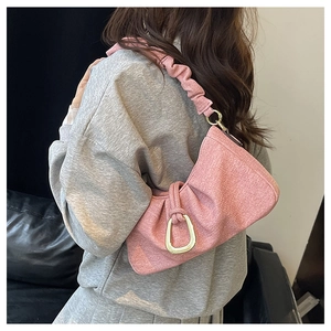 Detailed shot of pink woven shoulder bag with golden D-ring buckle and ruched strap