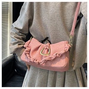 Detail of pink ruched shoulder bag featuring a gold U-shaped clasp and pleated trim