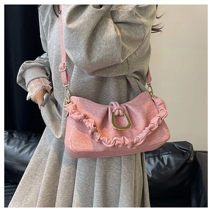 Close-up of pink tweed shoulder bag featuring ruffled edges and golden D-ring buckle
