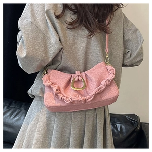Detail of pink pleated crossbody bag with gold horseshoe buckle worn on shoulder