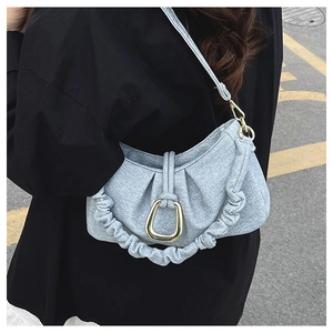 Detail of light blue textured fabric shoulder bag with stylish pleats and gold buckle