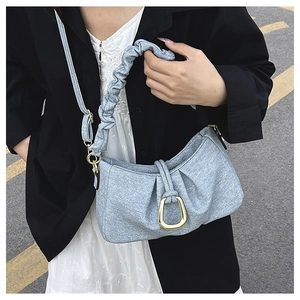 Detail of light blue pleated cloud bag featuring golden horseshoe buckle and ruched strap