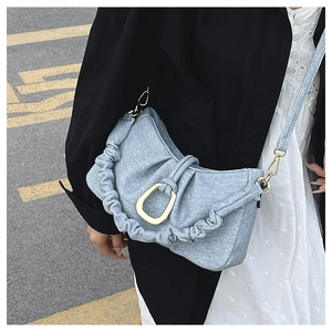 Detail of light blue ruched shoulder bag featuring a large gold U-shaped metal ring buckle