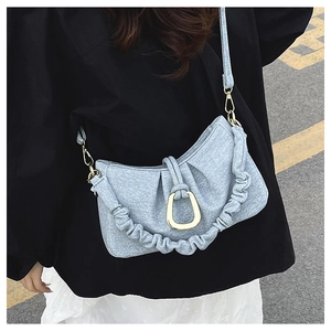 Detail of light blue pleated fabric underarm bag with gold U-shaped buckle on a model