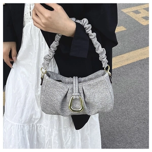 Close-up of grey pleated cloud bag with textured fabric and elegant gold metal buckle