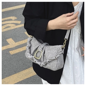 Detail of grey tweed shoulder bag with golden horseshoe buckle and ruffled pleated edges