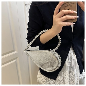 Close-up of a silver heart-shaped evening bag with sparkling rhinestone edges