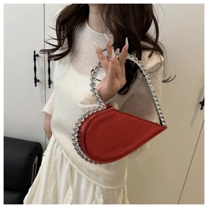 Close-up of bright red heart-shaped evening bag with crystal-encrusted handle detail