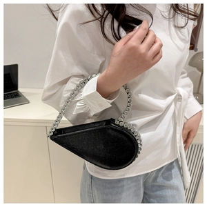 Close-up of a black heart-shaped evening bag with a sparkling silver rhinestone handle