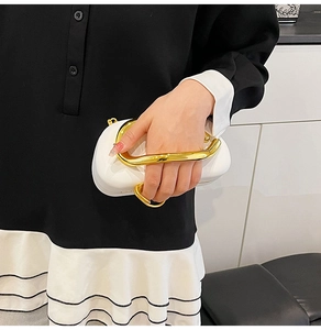 Close-up of white leather evening bag featuring a unique gold metallic ring handle