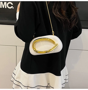 Detailed view of white oval crossbody bag with gold metal ring buckle and chain strap