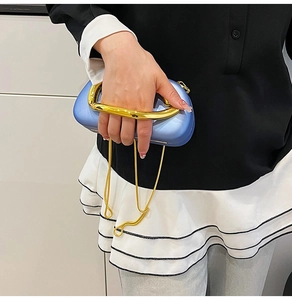 Detail of light blue hardshell clutch with thick gold handle and thin chain strap