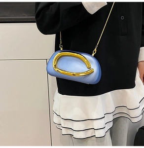 Close-up of light blue hard shell clutch with large gold metal handle and chain strap