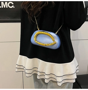 Detail of light blue crossbody bag with gold C-shaped metal clasp and chain strap