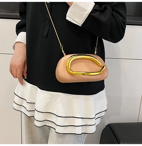 Detail view of pink half-moon crossbody bag with large golden C-shaped metal buckle and chain