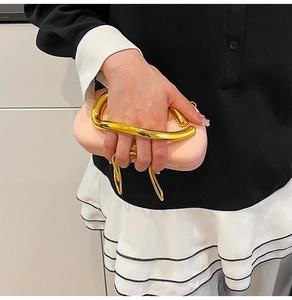 Detail view of pink hard shell clutch bag with stylish golden streamlined metal handle