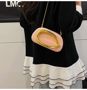 Detail of pink leather evening clutch bag with oversized gold metal buckle and chain strap