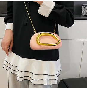 Pink mini box bag with gold U-shaped metal handle and chain strap on shoulder