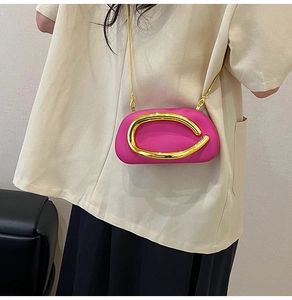 Detail of fuchsia mini crossbody bag with gold metal ring on model from side view