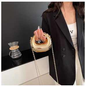 Detail of golden crescent metal evening bag with fine chain strap in modern setting