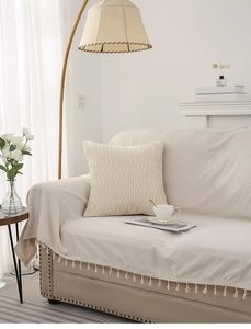 Detailed cream textured throw pillow with pleats and fringed sofa cover in cozy room
