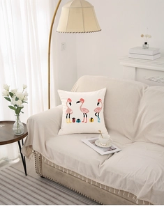 Close-up of festive flamingo throw pillow on a cozy sofa in a bright living room setup