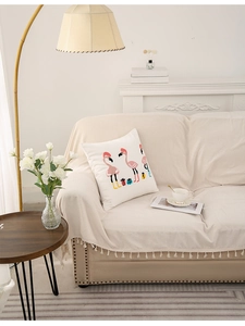 Detail of flamingo print pillow and beige tassel sofa throw in cozy living room