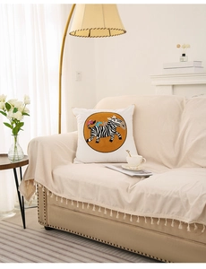 Detail of a white square pillow cover featuring a cute zebra print on a soft fabric sofa