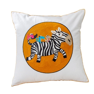Square throw pillow with zebra and animal embroidery on white background with gold piping