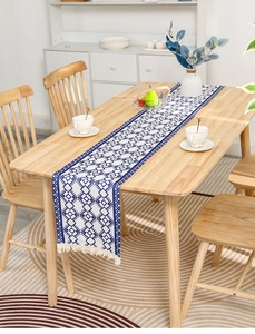 Detail of blue and white geometric striped table runner with white fringe on a wooden table