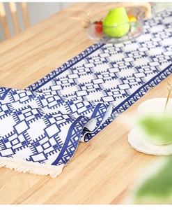 Close-up of Nordic blue and white geometric table runner with handmade tassels on wood