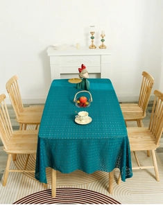 Detailed peacock blue lace tablecloth with hollow geometric patterns on wooden table
