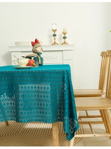 Close-up of peacock blue lace tablecloth with hollow patterns on wooden dining table