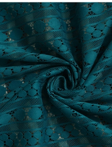Detail of dark teal hollow lace tablecloth with geometric circular and stripe patterns