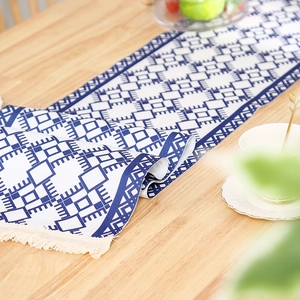 Nordic woven table runner with blue geometric patterns and handmade tassels on wood table