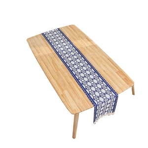 Blue and white geometric table runner with cotton tassels on a wooden surface