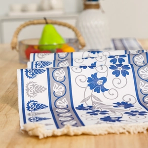 Nordic cream table runner with blue floral print and handmade tassels on wooden table