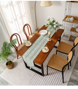 Close-up of sage green cotton linen table runner with white geometric patterns and tassels