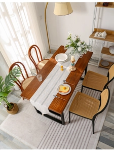 Close-up of beige woven table runner with striped patterns and handmade tassels on wood table